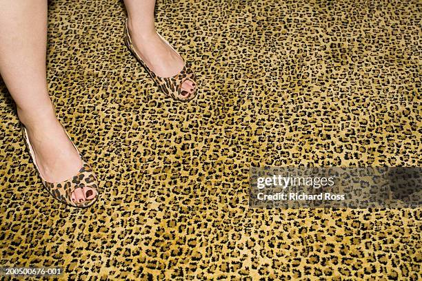 young woman in cheetah-print shoes standing on cheetah-print carpet - camouflage photography stock-fotos und bilder