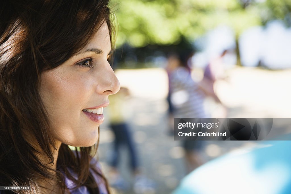 Young woman outdoors, smiling, side view, close-up