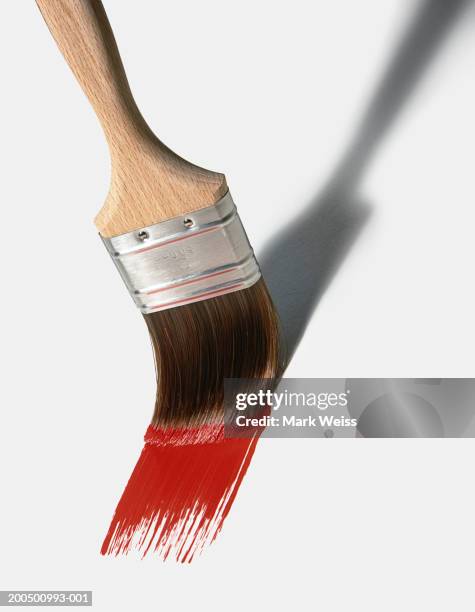 paint brush spreading red paint - paint brushes stock pictures, royalty-free photos & images