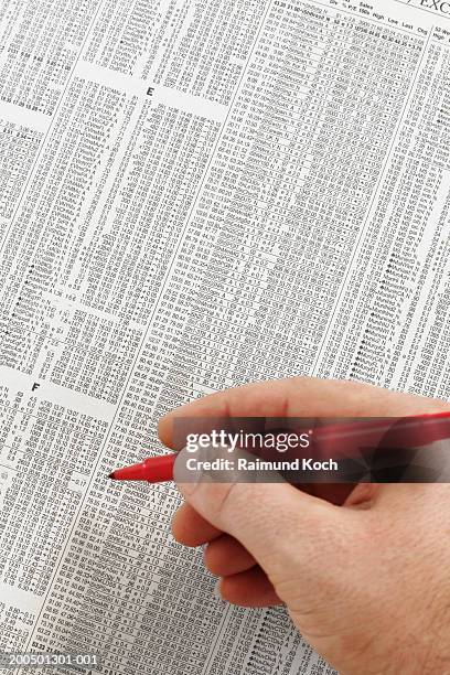 man holding red pen by stock quotes in newspaper, close-up - escrita ocidental imagens e fotografias de stock
