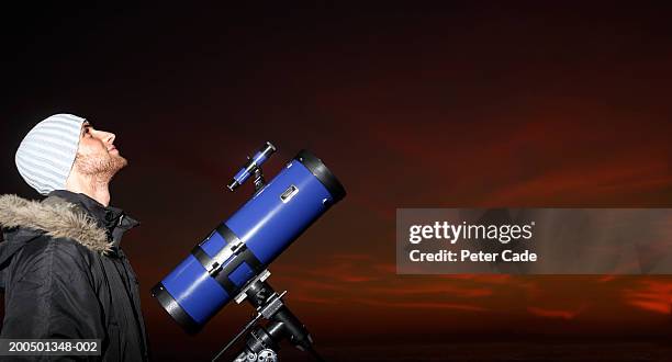 young man with telescope looking at sky, dusk, side view - 望遠鏡　男性 ストックフォトと画像