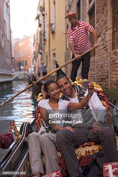 italy, venice, couple riding in gondola, woman taking digital photo - venedig gondel stock-fotos und bilder