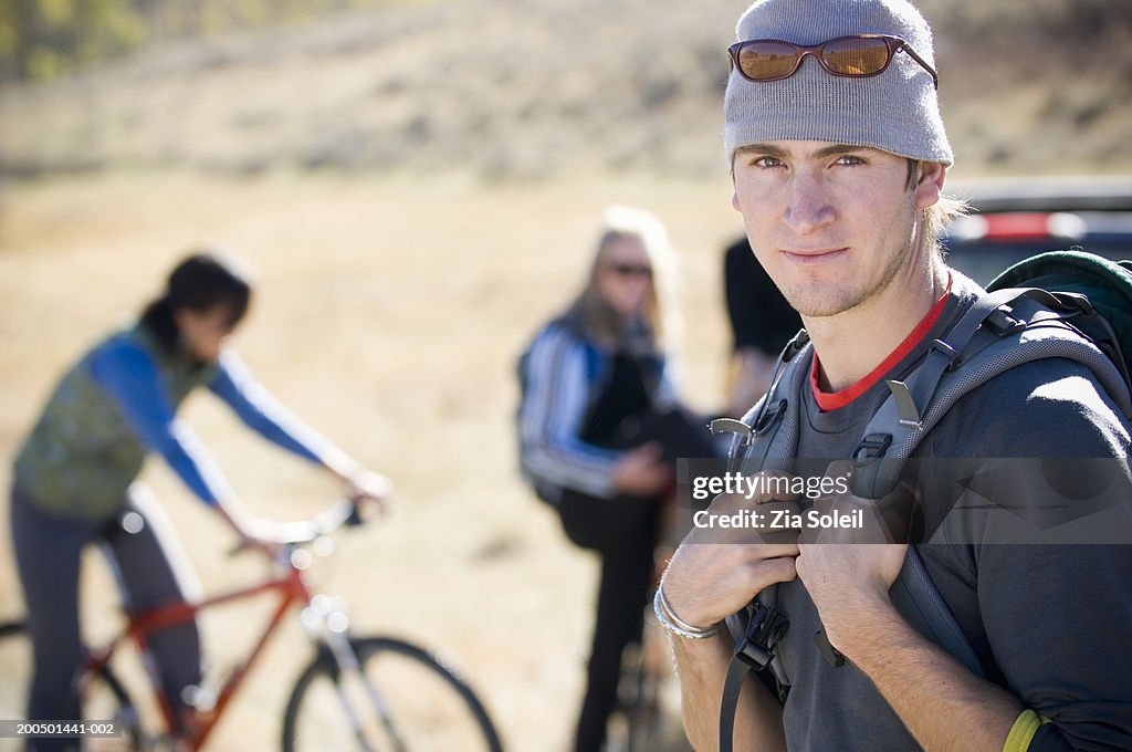 Young man with rucksack on hiking excursion, smiling, portrait