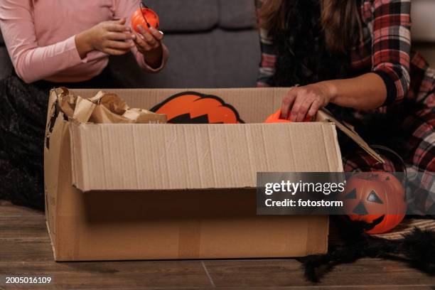 mother and daughter unpacking a box with halloween decorations - mother daughter halloween costumes stock pictures, royalty-free photos & images