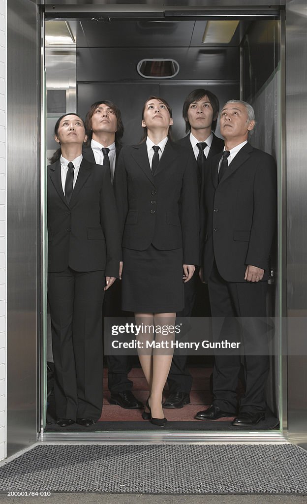 Five executives standing in elevator, looking up