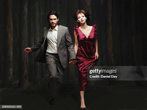 elegant couple running in front of painted trees - evening wear ストックフォトと画像