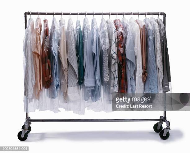 dry-cleaned clothes wrapped in plastic hanging on clothes rack - dry cleaning photos et images de collection