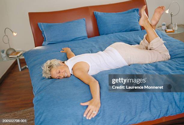 senior woman lying on bed, smiling - woman smiling facing down stock pictures, royalty-free photos & images