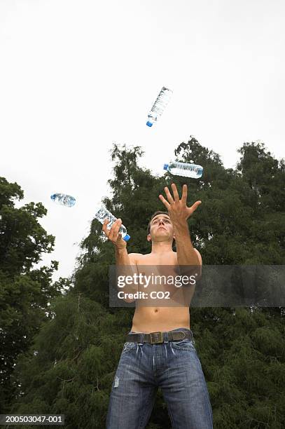 young man juggling with bottles of water in park, low angle view - juggling stock pictures, royalty-free photos & images