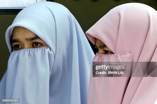 Two women with full headscarves wait for a bus after office hours in Kuala Lumpur, 24 July 2001. Malaysian Prime Minister Mahathir Mohamad has vowed...