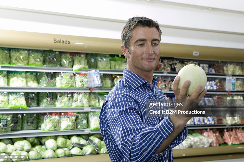 Man looking at melon in supermarket