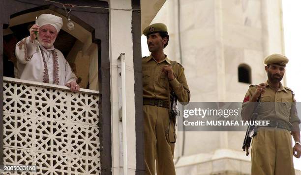 The head priest of the Hazratbal shrine in Srinagar shows a hair strand of Prophet Muhammed's beard to Muslim devotees as security personnel look on...