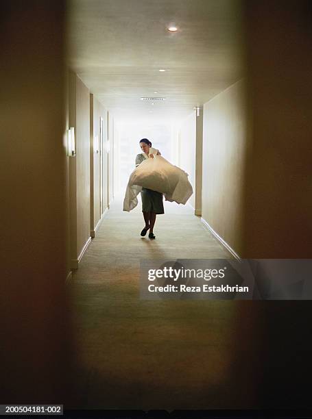 hotel cleaning staff carrying laundry in hallway - aide ménagère photos et images de collection