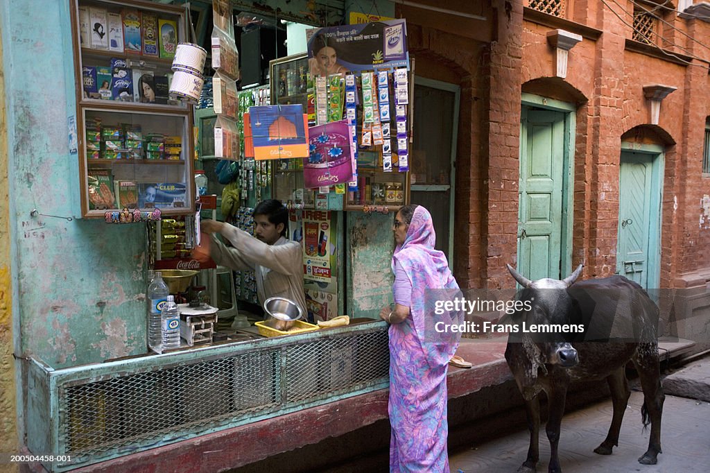 Woman walking cow outside street shop