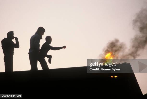 United Kingdom, Northern Ireland, Belfast Three youths set fire to a building roof top during the Troubles