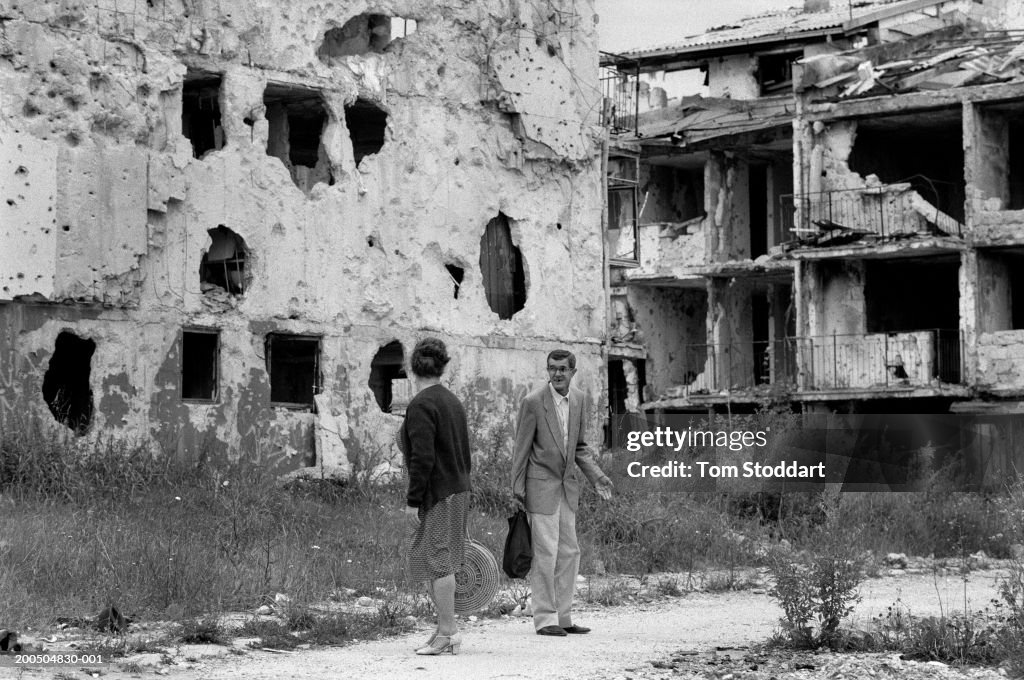 Bosnia, Sarajevo, Two men talking in street surrounded by destroyed houses