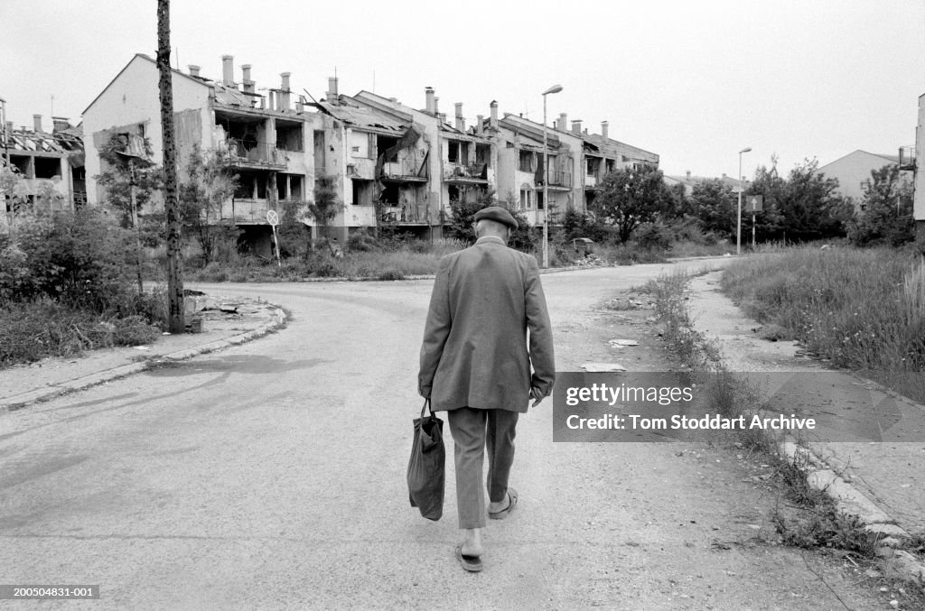 Bosnia, Sarajevo, Man walking through deserted street