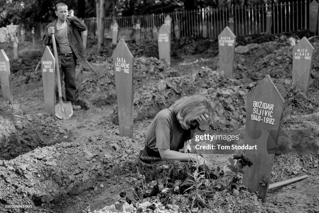 Bosnia, Sarajevo, Woman grieving by grave in Lion Cemetery