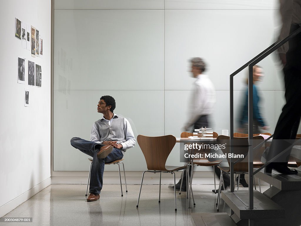 Colleagues walking in board room, man looking at picture on wall