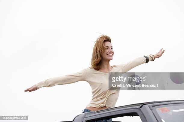 young woman on car, arms outstretched, smiling - soltak bildbanksfoton och bilder
