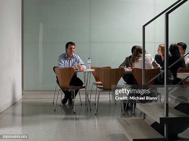 female colleagues having meeting in board room, man sitting alone - außenseiter stock-fotos und bilder