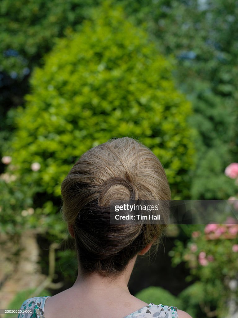 Mature woman standing in garden, close-up, rear view