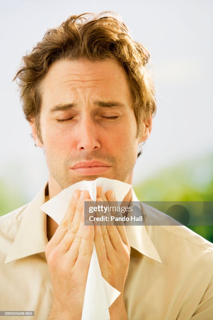 Mature man holding tissue, eyes closed, close-up