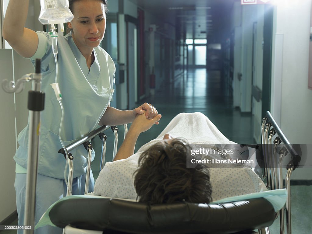 Female nurse by patient on bed walk in hospital