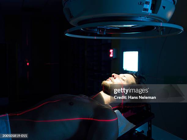 young male patient lying under radiology machine - radiotherapy stock pictures, royalty-free photos & images