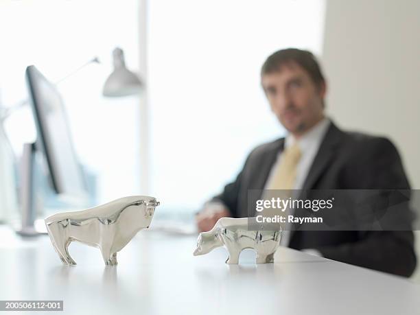 businessman looking at silver model animals on desk - bull bear stock pictures, royalty-free photos & images