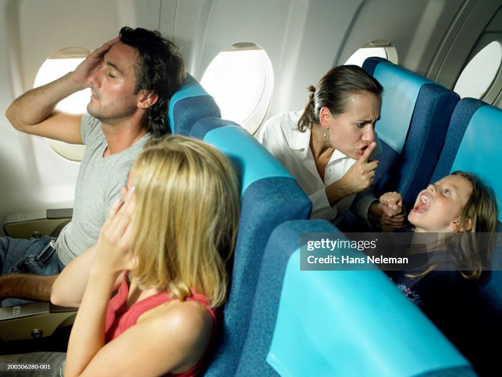 Girl (5-7) yelling behind young couple in airplane