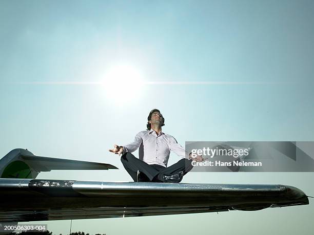 young man meditating on wing of airplane - aircraft wing stock pictures, royalty-free photos & images