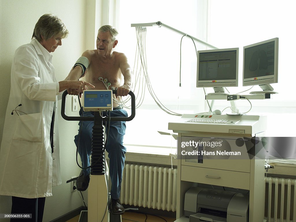 Senior female doctor by male patient having cardiology test