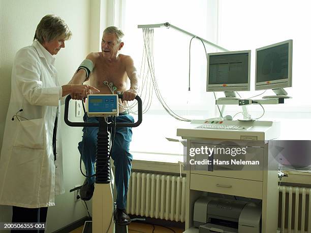 senior female doctor by male patient having cardiology test - cardiologist stock pictures, royalty-free photos & images
