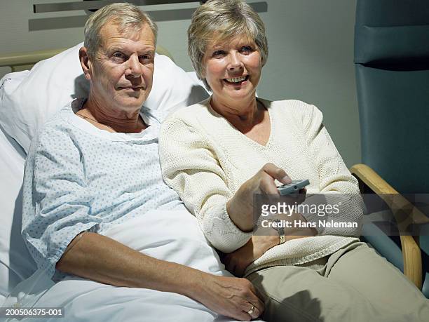 senior male patient and senior woman sitting on hospital bed - adult male hospital bed stock-fotos und bilder