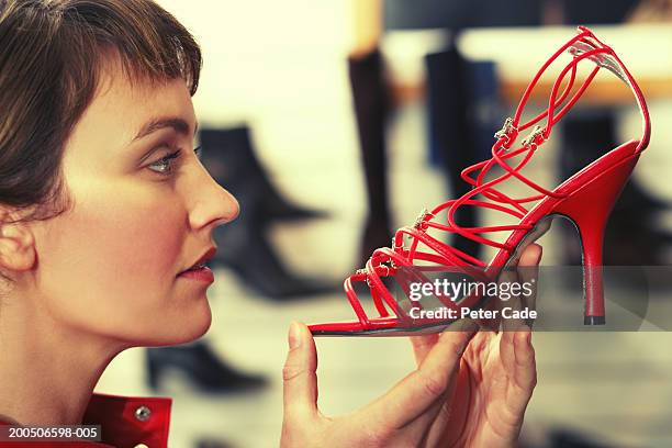 young woman holding red high heel, close-up - shoe store stock pictures, royalty-free photos & images