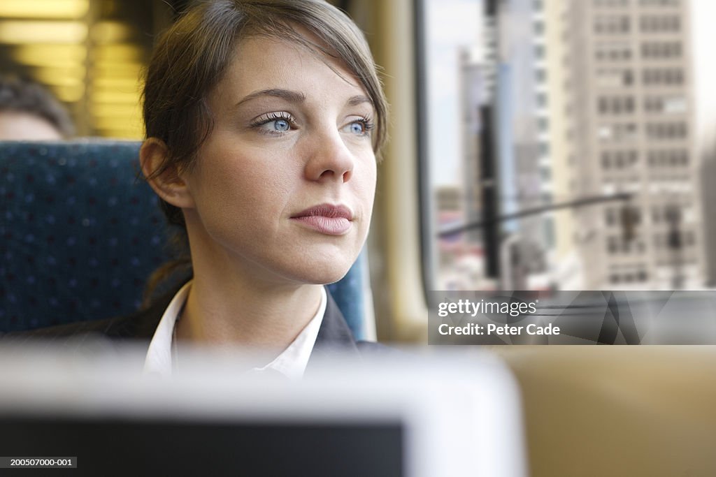 Businesswoman looking out window on train, close-up