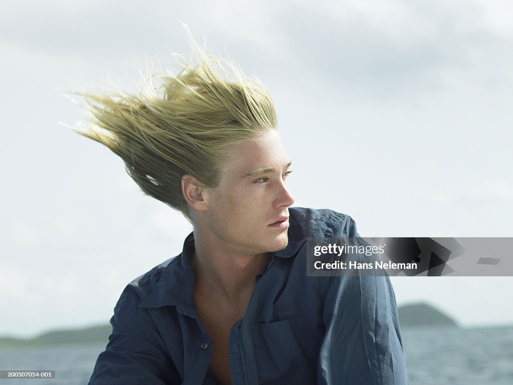 Young man outdoors, hair blowing in wind