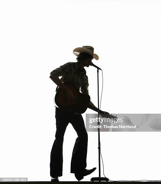 young man in cowboy hat playing acoustic guitar and singing - acoustic guitar white background stock pictures, royalty-free photos & images