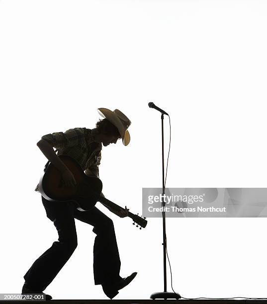 young man in cowboy hat playing acoustic guitar, side view - acoustic guitar white background stock pictures, royalty-free photos & images