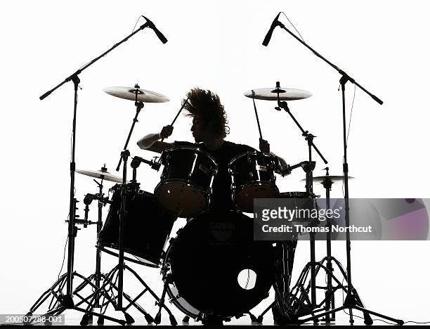 silhouette of young man playing drums, tossing hair - ドラム ストックフォトと画像