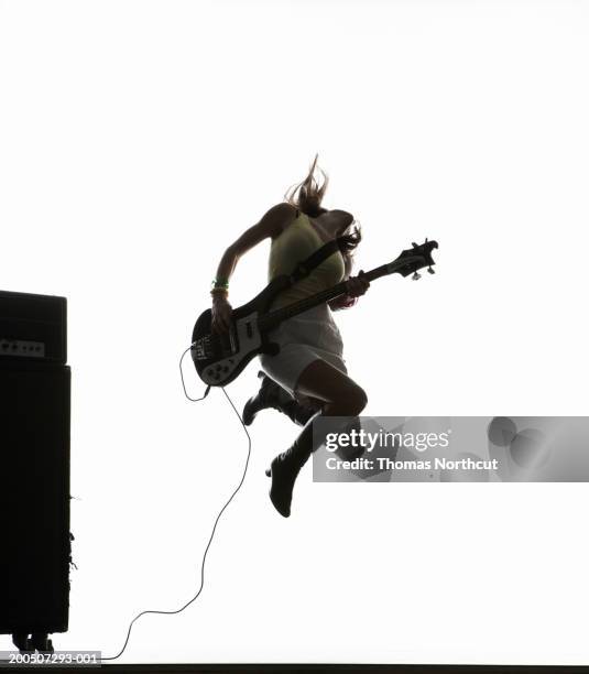 young woman jumping and playing bass guitar, head back - bass player bildbanksfoton och bilder