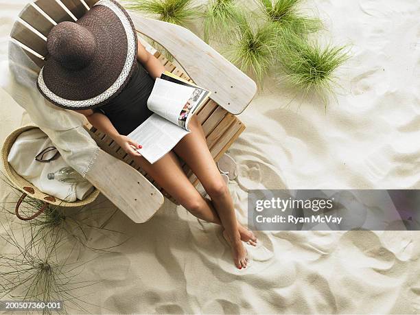 young woman reading magazine on adirondack chair, overhead view - zac efron celebrates the september issue of details magazine stockfoto's en -beelden