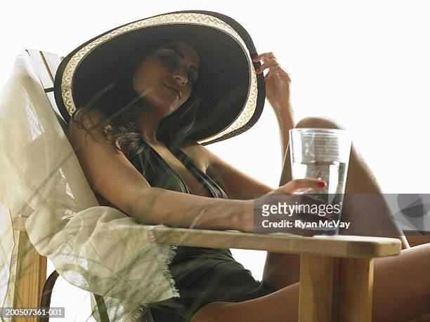 young woman with glass of water sitting on adirondack chair, portrait - adirondack chair closeup stock pictures, royalty-free photos & images