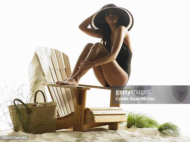 young woman sitting on adirondack chair in sand - adirondack chair white background stock pictures, royalty-free photos & images