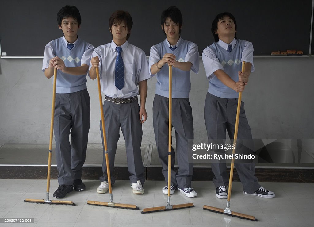 Teenage male students (13-17) with brooms, portrait