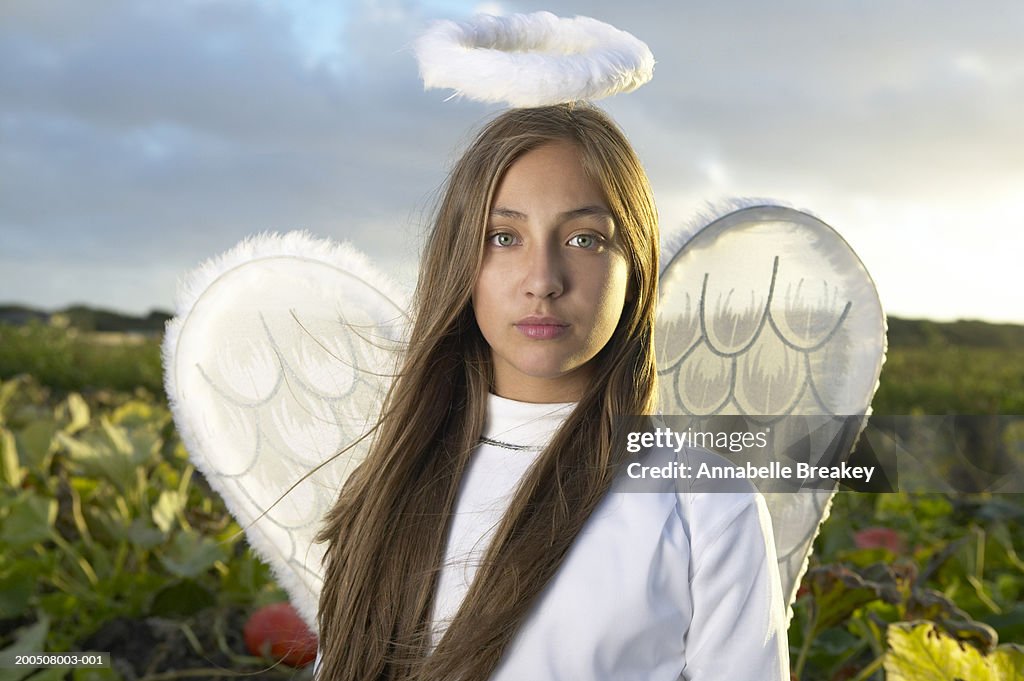 Teenage girl (12-14) wearing angel costume in pumpkin patch
