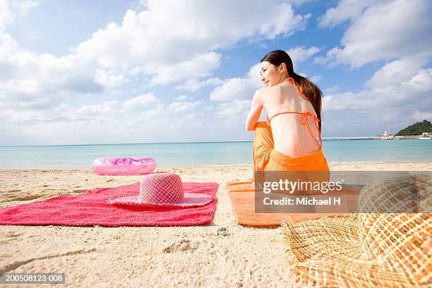 young woman sitting on towel on beach, rear view - michael sit stock pictures, royalty-free photos & images