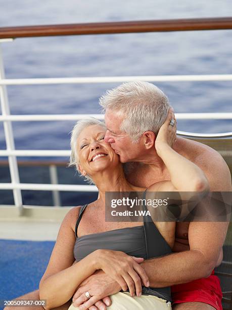 mature couple embracing on deck of ship, smiling - cruise deck stock pictures, royalty-free photos & images