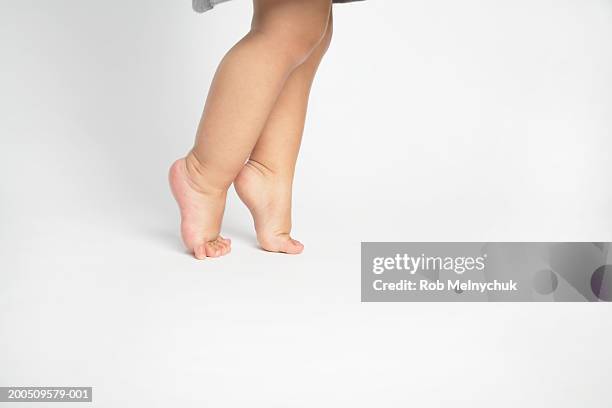 baby girl (15-18 months) walking on tiptoe, side view, low section - one baby girl only foto e immagini stock